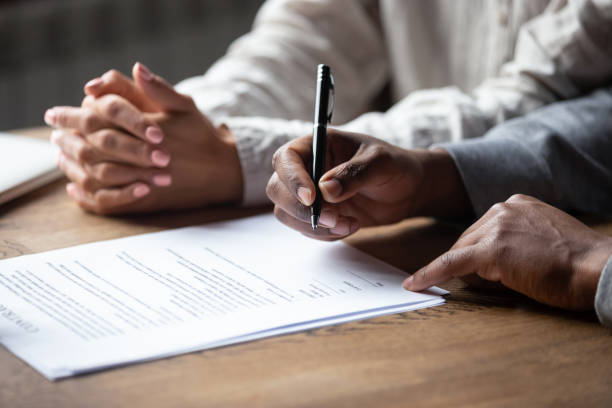 Close up of multiracial couple signing contract with Real Estate Agent Close up of african American husband put signature on contract buying first house with wife, multiracial couple sign agreement closing deal with Real Estate Agent or banker, taking property loan or mortgage legal document stock pictures, royalty-free photos & images