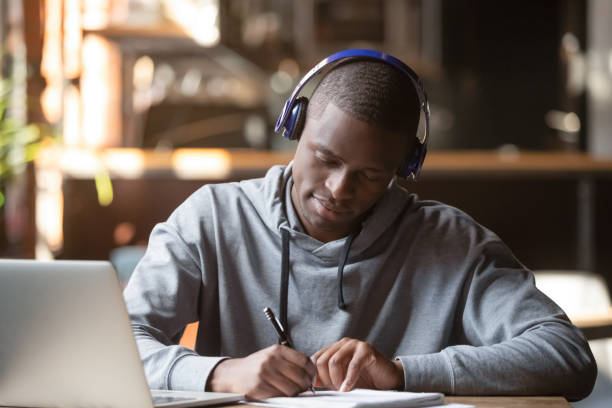 istock Concentrated black male student in Bluetooth headphones studying 1206334744