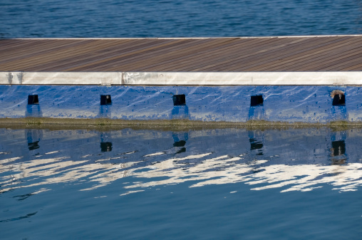 Colored floating pier and reflection on water surface in a marina.