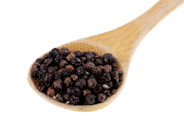 istock Spoon full of black peppercorns on a white background 1206346894