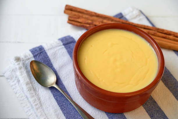 Catalan cream served in a clay bowl with a silver spoon, on top of a blue and white napkin stock photo