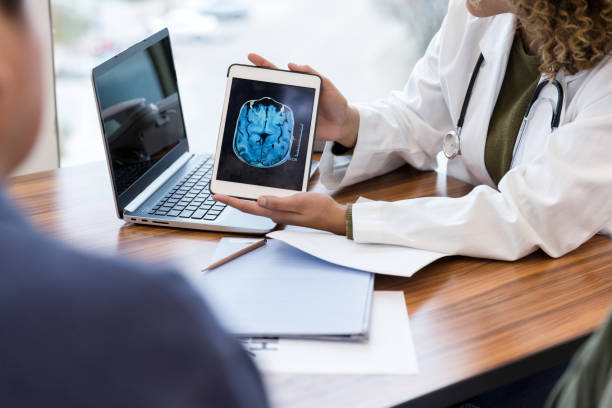 Neurologist reviews patient's brain MRI scan Unrecognizable female doctor shows a male patient an image of his brain from an MRI scan. The image is on a digital tablet. neurodegenerative disease stock pictures, royalty-free photos & images