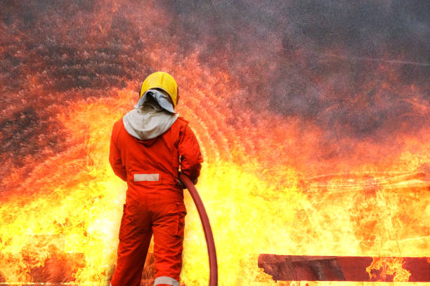 istock Firefighters training, Team practice to fighting with fire in emergency situation. A fireman carry a water hose run through flame 1206381421