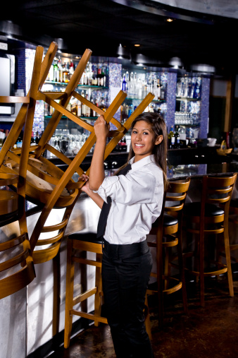 Pretty restaurant worker taking down chair from bar