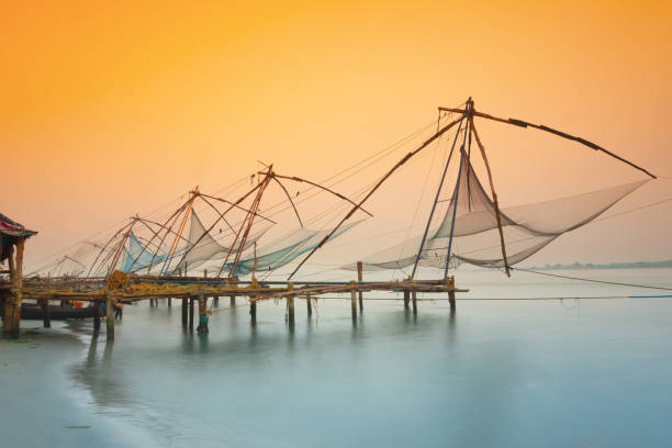 redes de pesca chinas tradicionales en kochi, india al amanecer - kerala fotografías e imágenes de stock