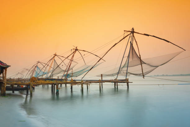 Traditional chinese fishing nets in Kochi, India at sunrise Chinese fishing nets in Fort Kochi, Kerala, India. kochi india stock pictures, royalty-free photos & images