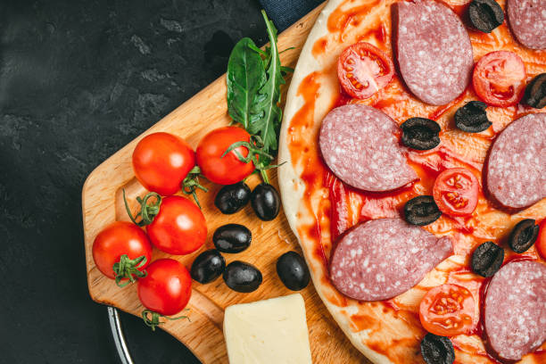 istock Process of making pizza round dough with black olives, cherry tomatoes, mozzarella cheese, sliced salami and green leaves spinach, rucola, top view 1206392333