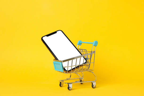 istock Phone with empty screen and shopping cart on yellow background, close up 1206392995
