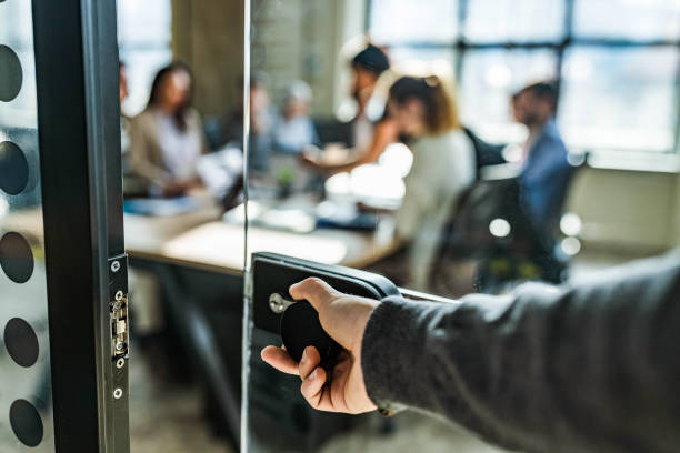 Close up of unrecognizable person opening office door. Close up of unrecognizable male person opening glass door to enter the office. There are people in the background. incidental people stock pictures, royalty-free photos & images