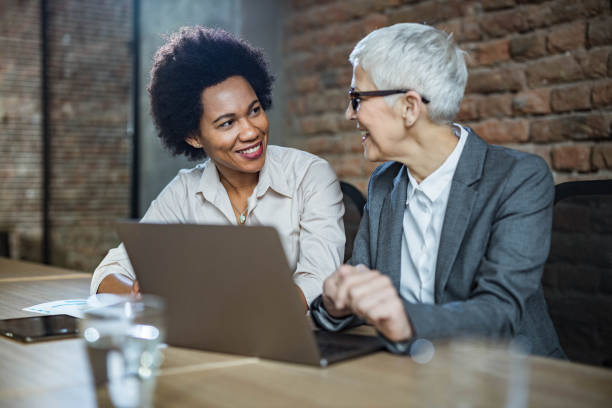 istock Happy female entrepreneurs talking while working on laptop in the office. 1206393991