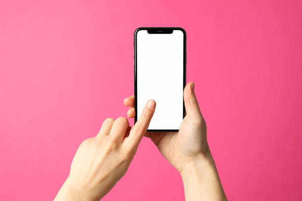 istock Female hands hold phone on pink background. Empty screen 1206394812