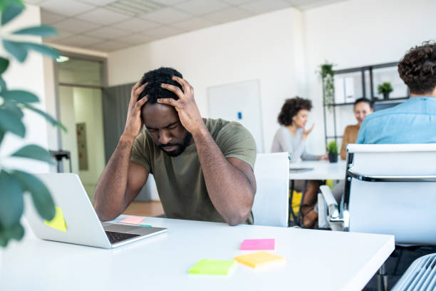 istock A young man stuck with a problem at work, holding his head and thinking hard. 1206395212