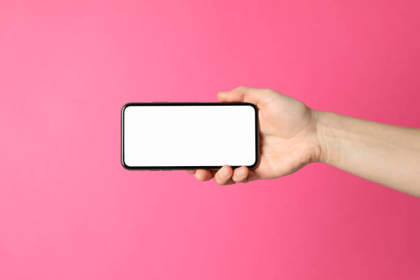 istock Female hand holds phone on pink background. Empty screen 1206395437