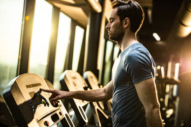 istock Athletic man adjusting speed while exercising on treadmill in a gym. 1206397932