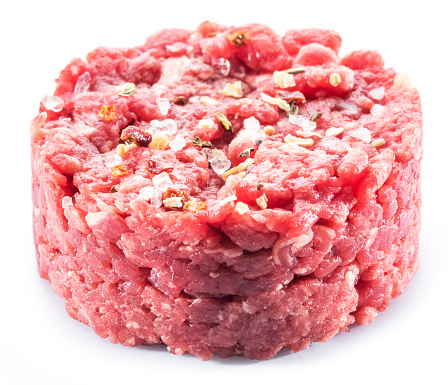 Ground cutlet or raw hamburger with seasonings on white background. Close-up.