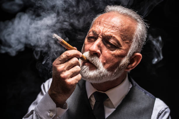 istock Serious senior man who is smoking cigar 1206402551
