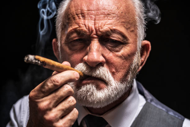 istock Serious senior man who is smoking cigar 1206402649