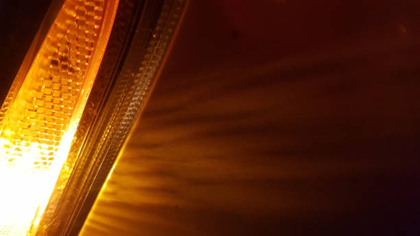 istock Defocused patterned surface of orange color headlight closeup on dark blurred background. Lights and striped rays in darkness. Abstract backdrop with copy space. 1206403077