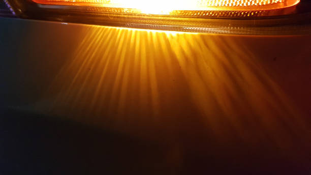 istock Golden red light of headlight closeup on dark blurred background. Shiny striped rays in darkness of night. Abstract backdrop with copy space. 1206403103