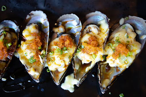 Fresh mussel baked with cheese on black plate