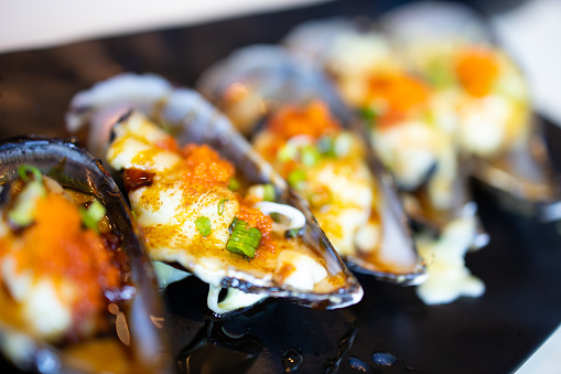 Fresh mussel baked with cheese on black plate