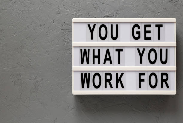 istock 'You get what you work for' words on a lightbox on a gray background, top view. Overhead, from above, flat lay. Copy space. 1206405802