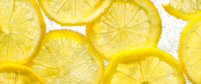 Slices of lemon in water with air bubbles on white. Close-up.