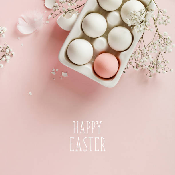 Easter eggs in white ceramic holder and flowers on pink background