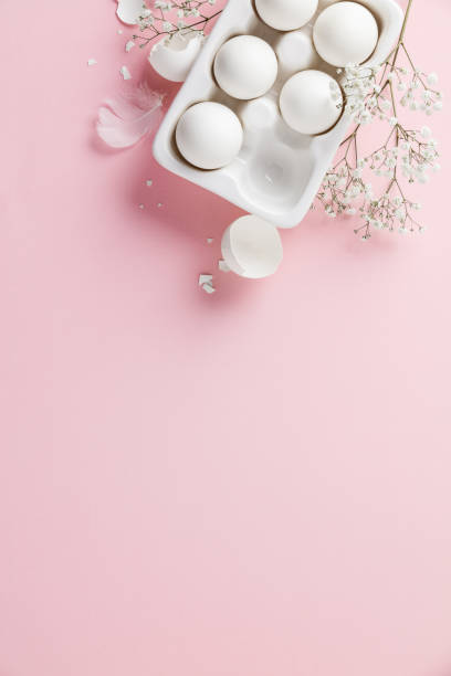 istock White eggs  in white ceramic holder and flowers on pink background 1206410181