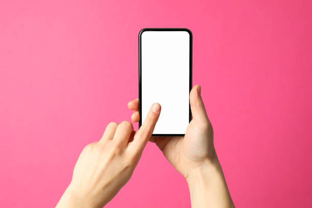 istock Female hands hold phone on pink background. Empty screen 1206410227
