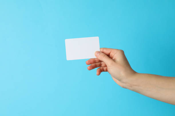 istock Female hand holding empty business card on blue background 1206410458