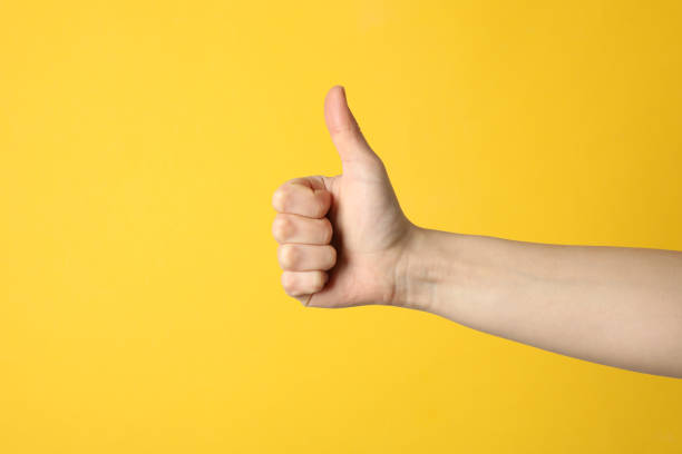 istock Female thumbs up on yellow background, space for text 1206410491