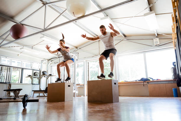 Man and woman working out jumping on box