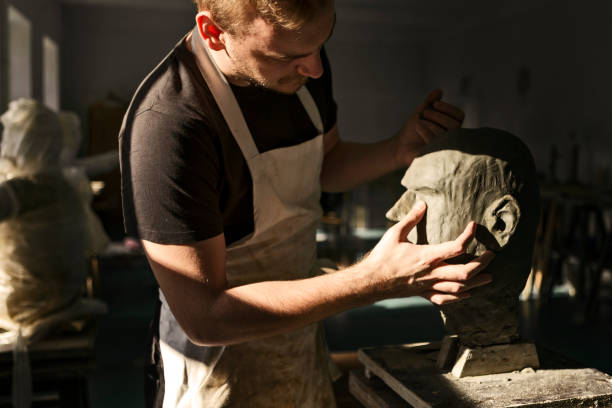 粘土の頭の彫刻に取り組む彫刻家 - shaping clay ストックフォトと画像