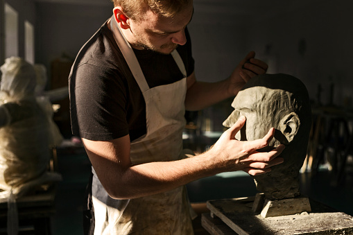 Sculptor working on his clay head sculpture