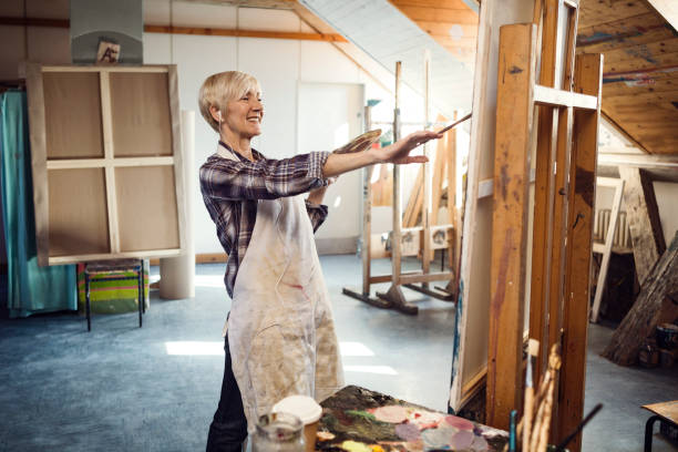 istock Senior woman in workshop painting on canvas 1206411814