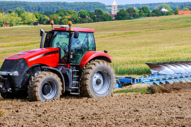 istock Farmer in red tractor preparing land with plow for sowing 1206412422