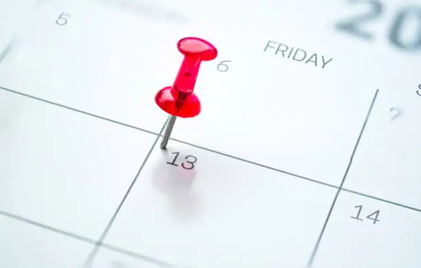 Red push pin on calendar friday the 13th day of the month
