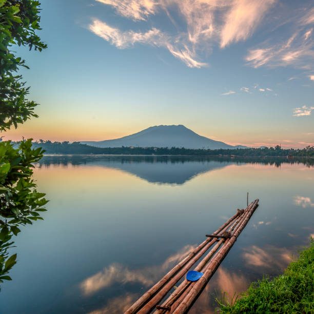 It evokes the stillness of life duplicated by the presence of bamboo raft over the smoothness of water and the mountain in the background.