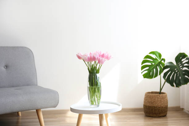 istock Glass vase with spring flowers on small white coffee table. 1206421407