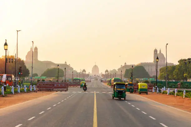 Sunset traffic in New Delhi, tuc tuc cars on the road to the Presidential Residance.