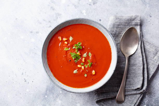 istock Tomato soup with fresh herbs and pine nuts in a bowl. Grey stone background. Top view. 1206424581
