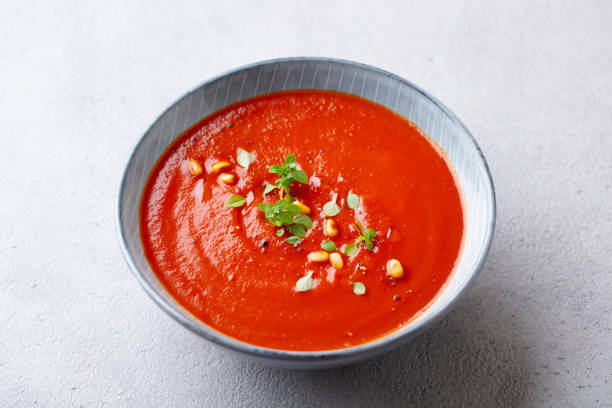 istock Tomato soup with fresh herbs and pine nuts in a bowl. Grey stone background. Close up. 1206425343