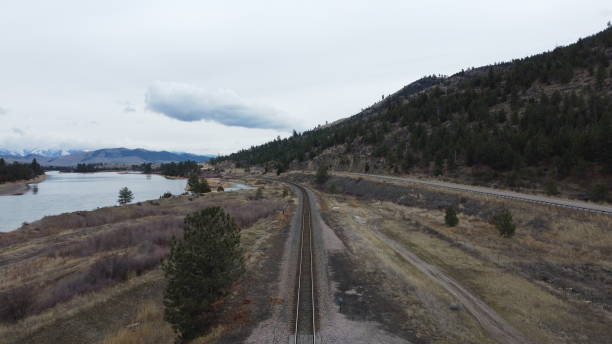 istock Train track and road bending around curve of mountain range with river on the side 1206425406