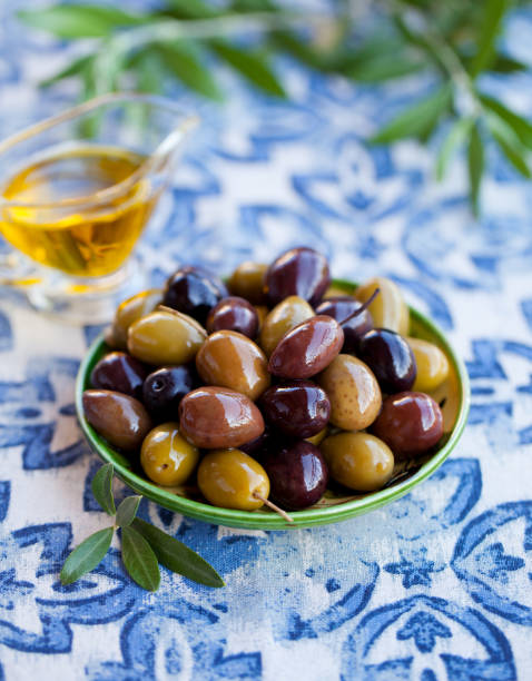 istock Assortment of fresh olives on a plate with olive tree brunches. Blue textile background. 1206430947