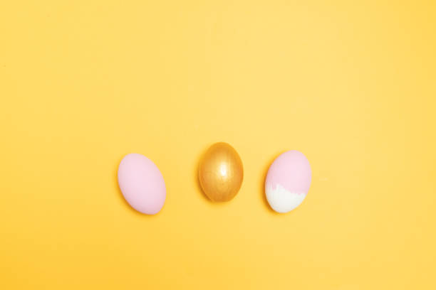 istock Gold and pink egg on a yellow background 1206433249