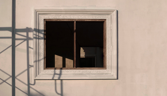 Front view of window frame with shadow of scaffold on surface of concrete wall in house building construction site