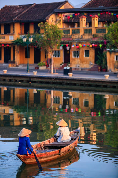 Vietnamese women riding a boat, old town in Hoi An city, Vietnam Vietnamese women in a row boat,, old town in Hoi An city, Vietnam. Hoi An is situated on the east coast of Vietnam. Its old town is a UNESCO World Heritage Site because of its historical buildings. hoi an stock pictures, royalty-free photos & images