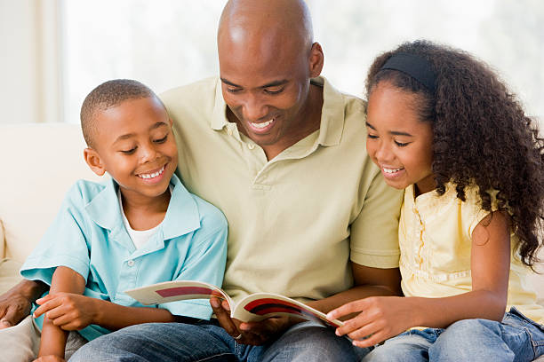 homme se dresse et lit un livre avec deux enfants - family reading african descent book photos et images de collection