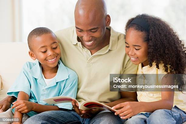 Man Sits And Reads A Book With Two Children Stock Photo - Download Image Now - Reading, Father, African-American Ethnicity